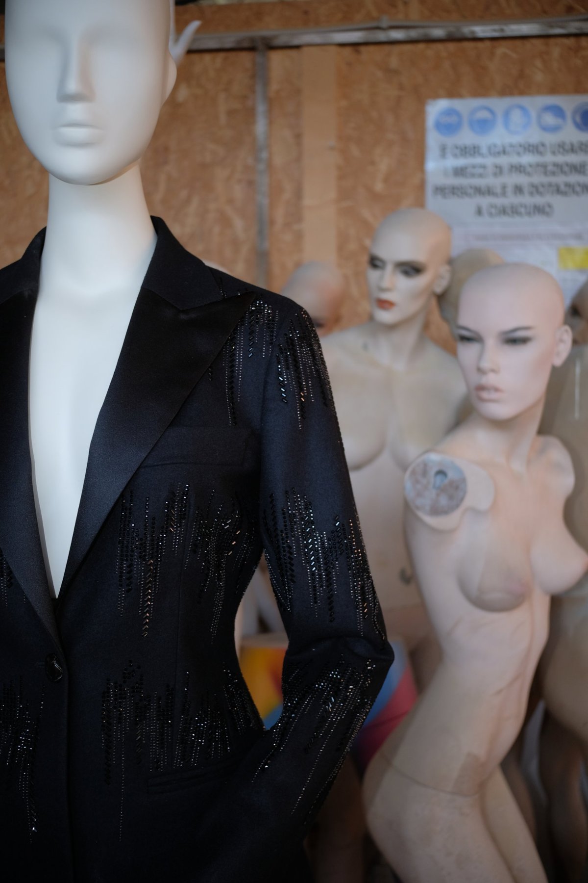 a black beaded jacket with a satin lapel on a mannequin, other mannequins behind