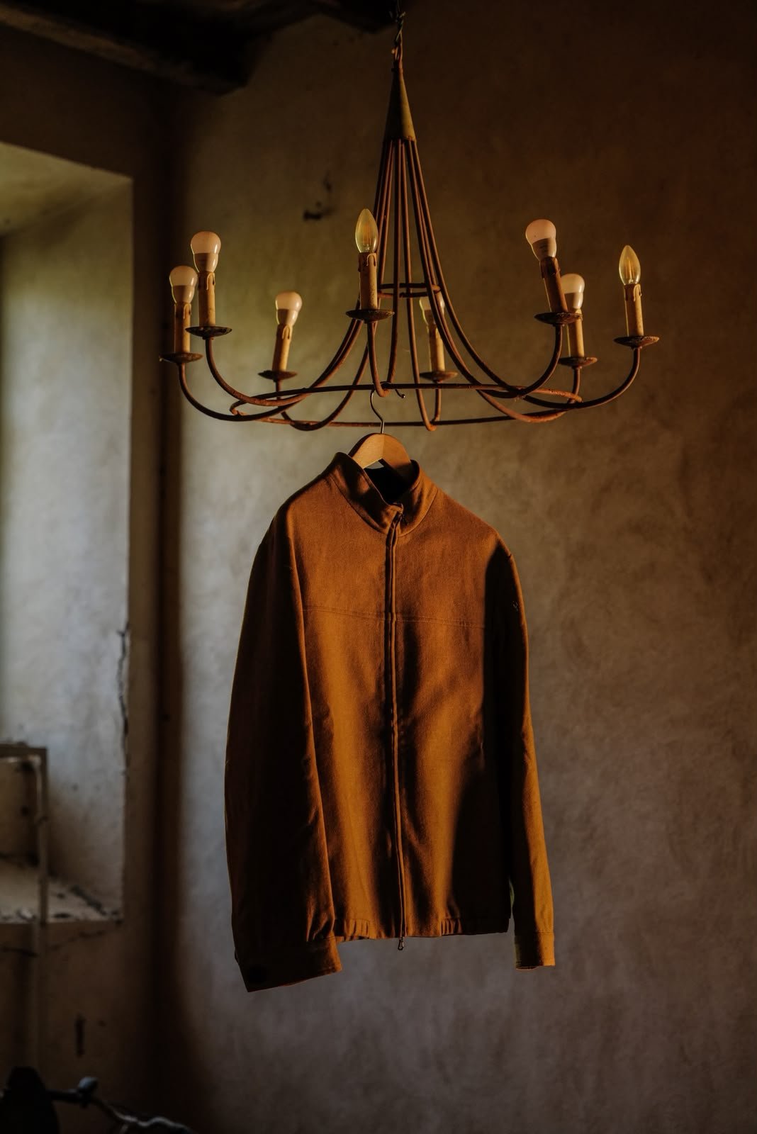 a rust-coloured zip jacket hanging from an iron chandelier