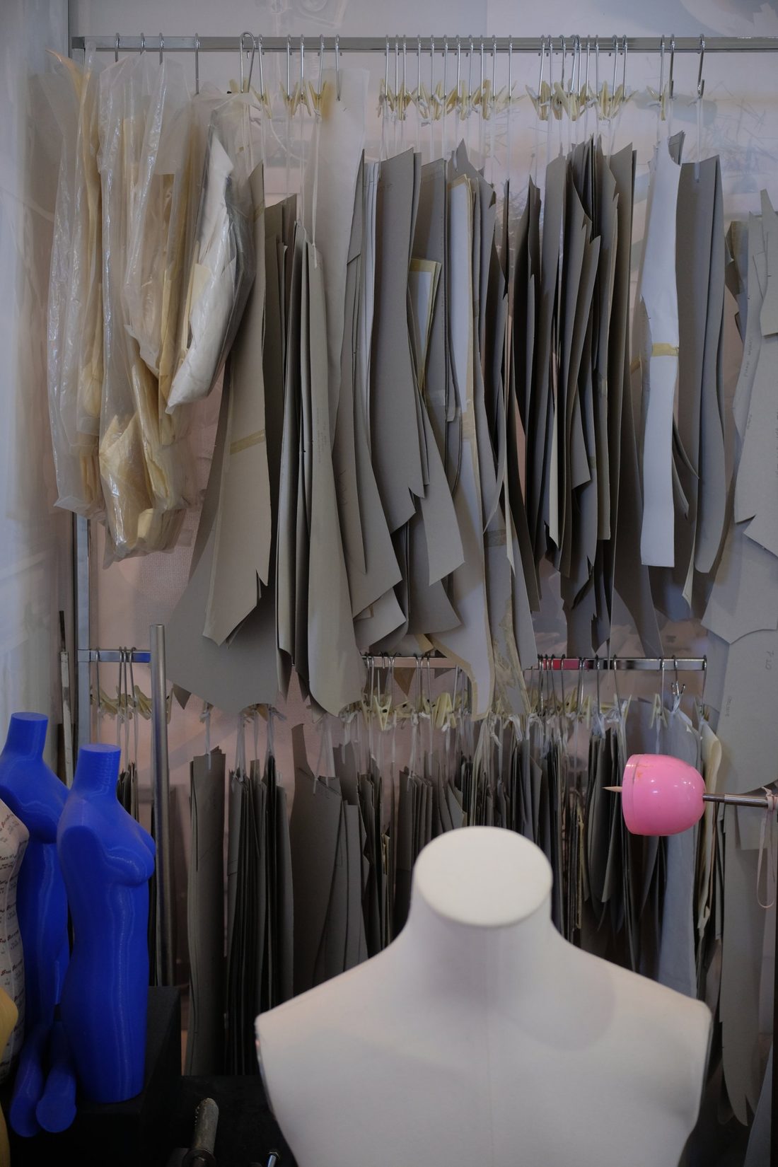 Paper patterns for coats hanging on rails in the atelier