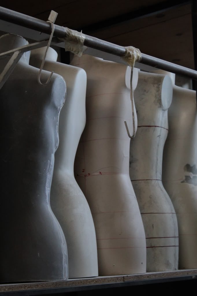A row of dress forms hanging from a rail
